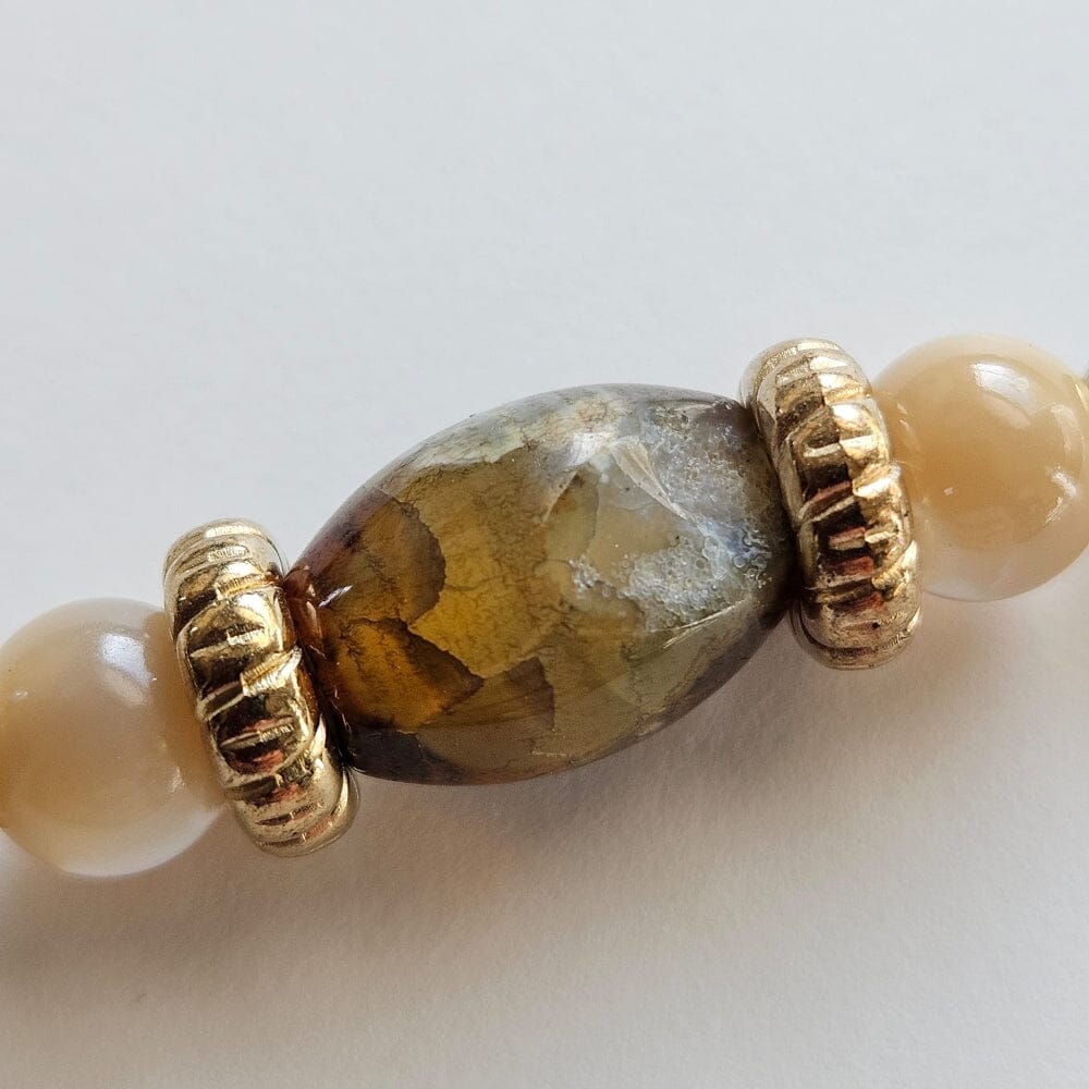 
                  
                    Fossilized ammonite pendant with tiger's eye beads, mother-of-pearl, gold-filled spacers, gold-color metal rondelles, chalcedony barrel beads, and gold-plated clasp and findings.
                  
                