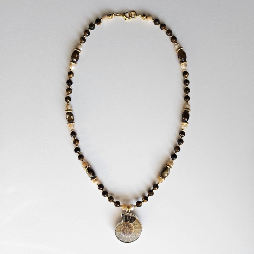 
                  
                    Fossilized ammonite pendant with tiger's eye beads, mother-of-pearl, gold-filled spacers, gold-color metal rondelles, chalcedony cylinders, and gold-plated clasp and findings.
                  
                