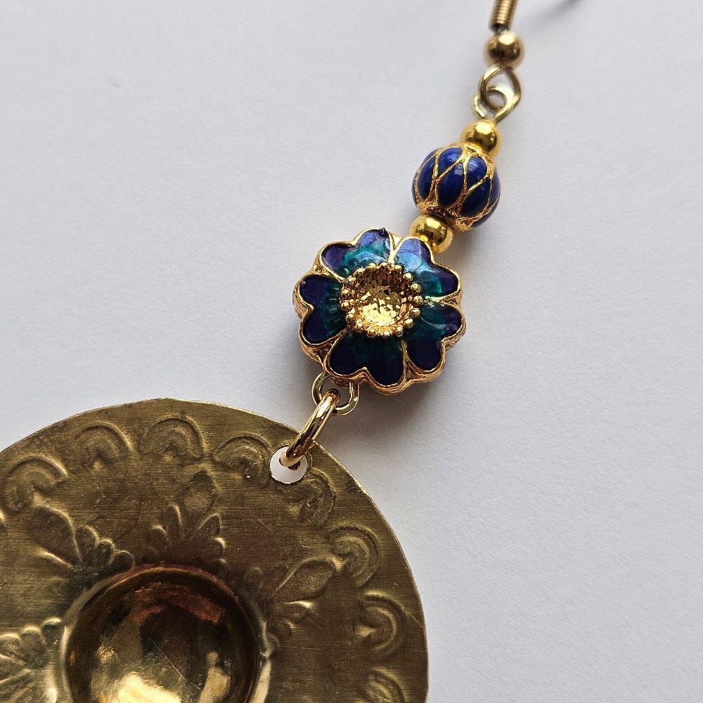 
                  
                    Gold-filled blue floral motif enamel bead, gold-filled alternating blue drop motif, gold-plated brass spacers, gold-plated stainless steel ear wire, brass agong medallion earrings.
                  
                