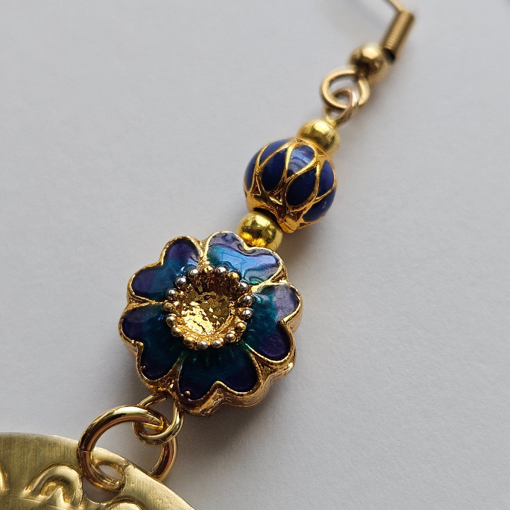 
                  
                    Gold-filled blue floral motif enamel bead, gold-filled alternating blue drop motif, gold-plated brass spacers, gold-plated stainless steel ear wire, brass agong medallion earrings.
                  
                