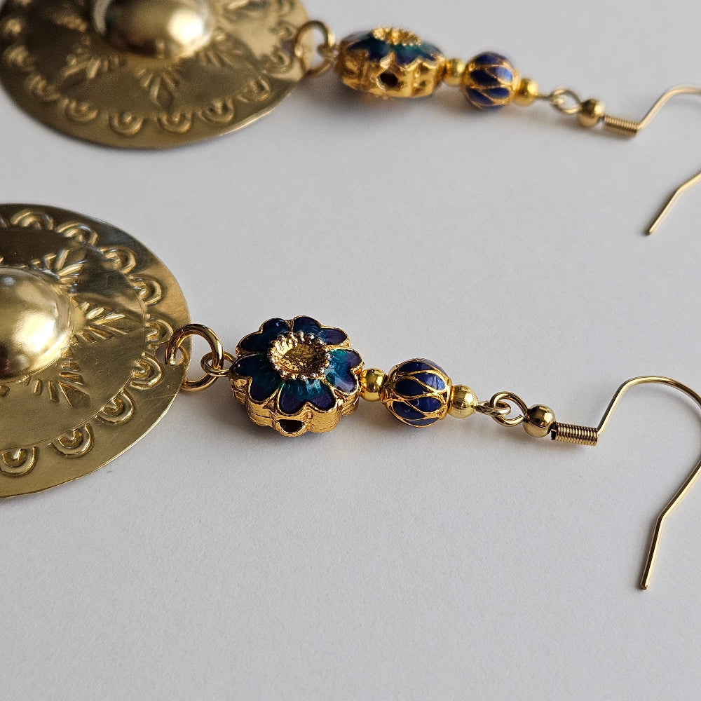 
                  
                    Gold-filled blue floral motif enamel bead, gold-filled alternating blue drop motif, gold-plated brass spacers, gold-plated stainless steel ear wire, brass agong medallion earrings.
                  
                