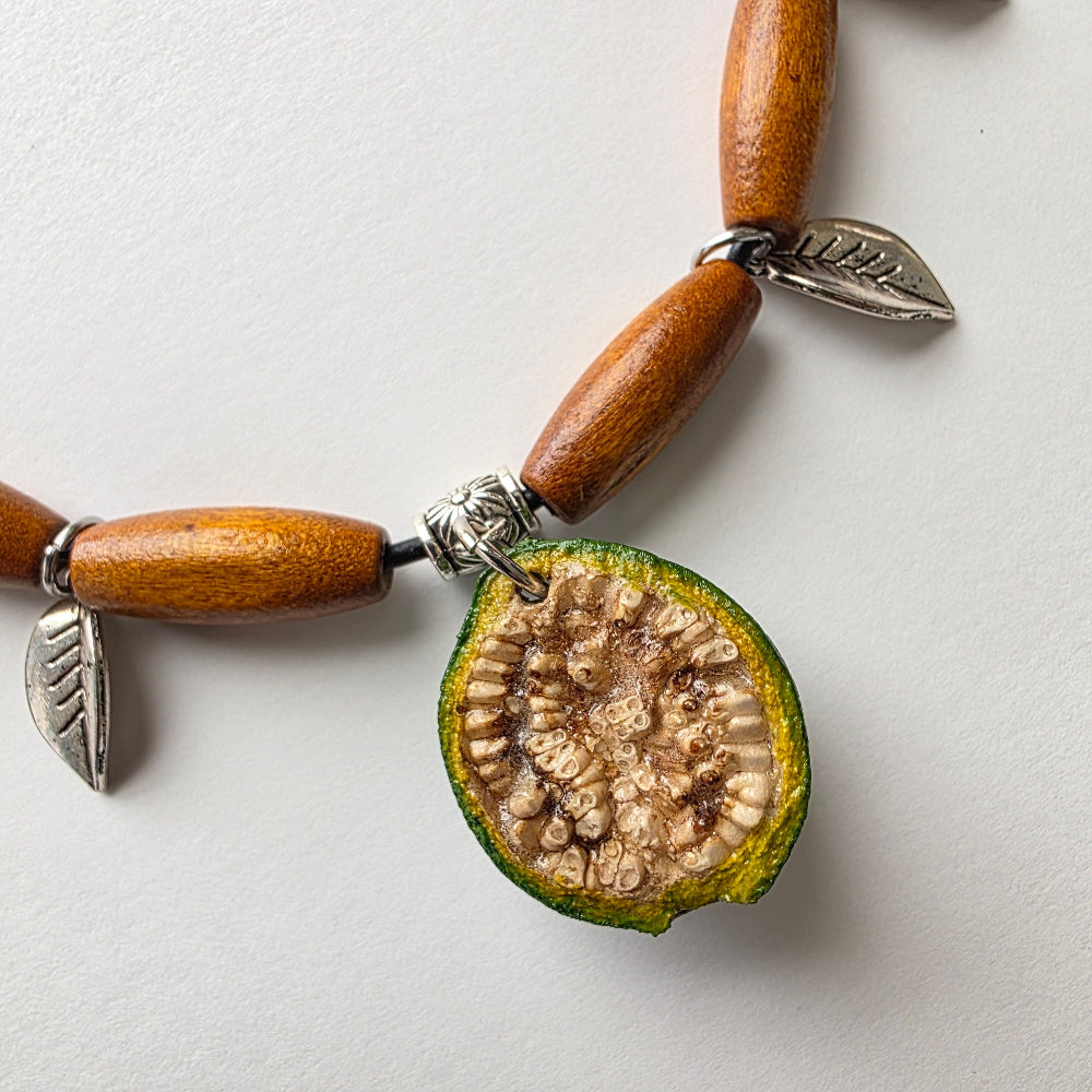 Guava fruit pendant with silver leaves and wood tubes.