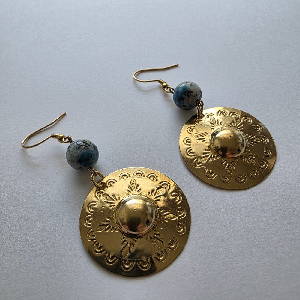 Gold earrings with blue beads on a light gray background