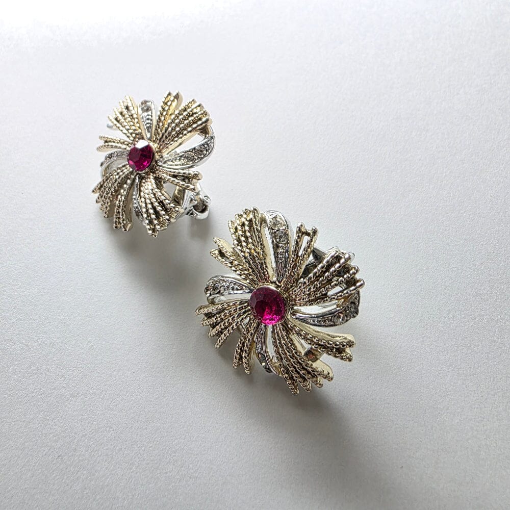 Pair of decorative earrings with red gemstones on a light gray background