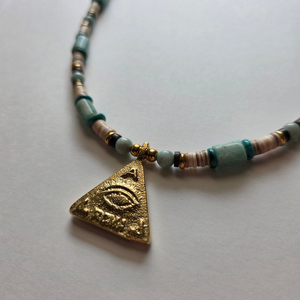 Necklace with a gold triangle pendant featuring an eye design on a light gray background