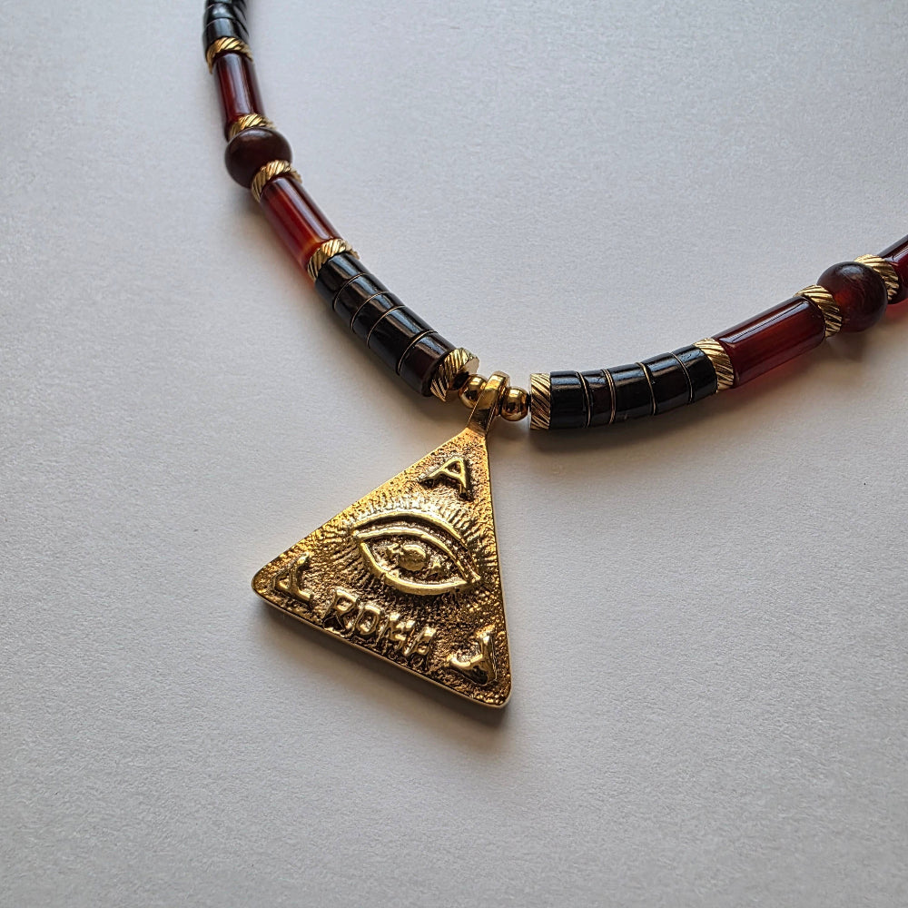 Necklace with a gold triangle pendant featuring an eye design on a light gray background