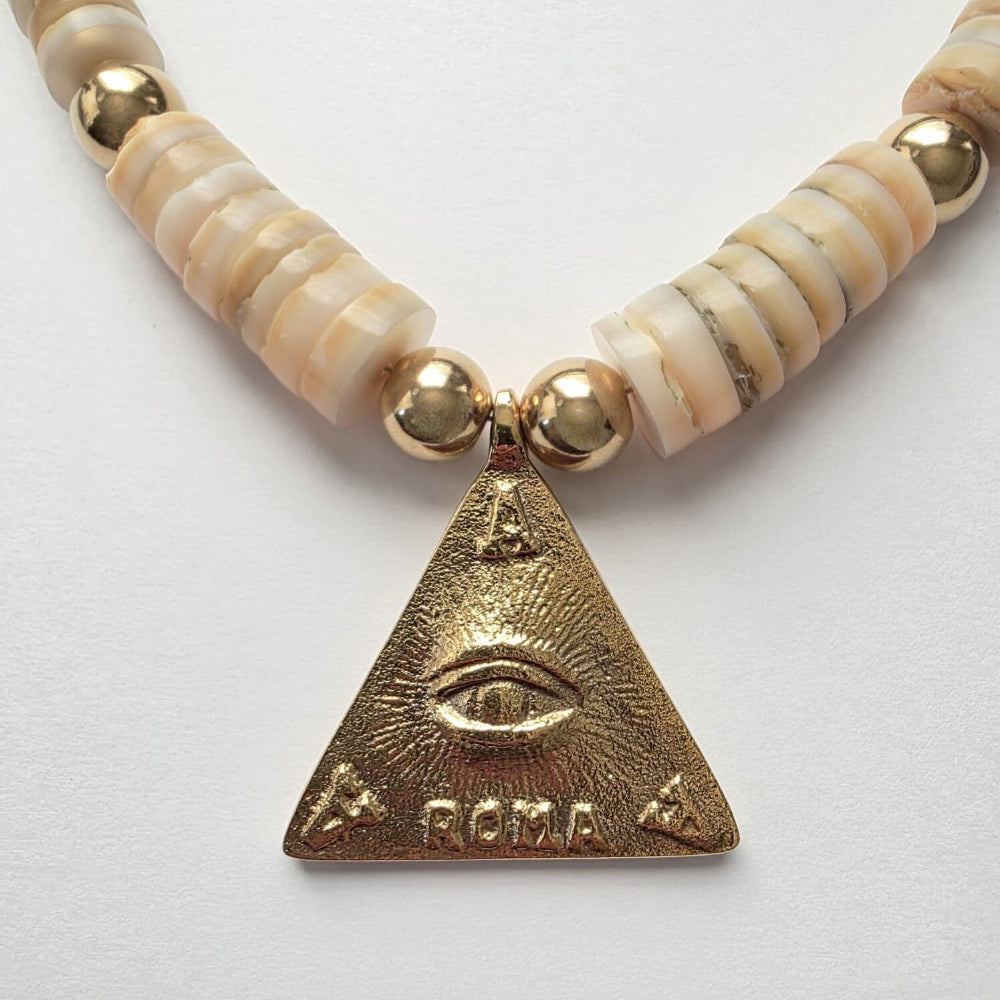 Necklace with gold and beige beads and a triangular pendant with 'Roma' engraving on a white background