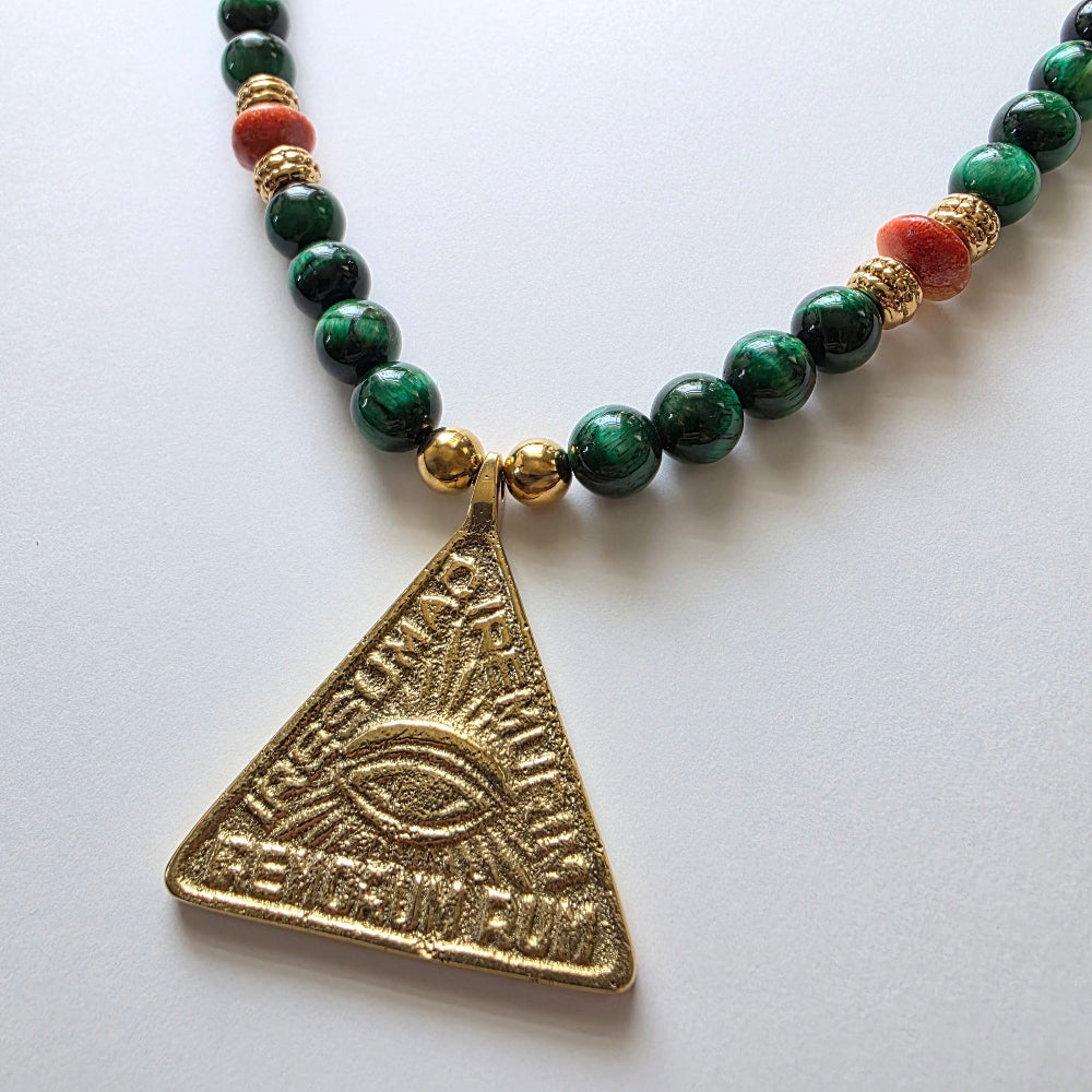 Necklace with green beads and a gold triangle pendant on a white background