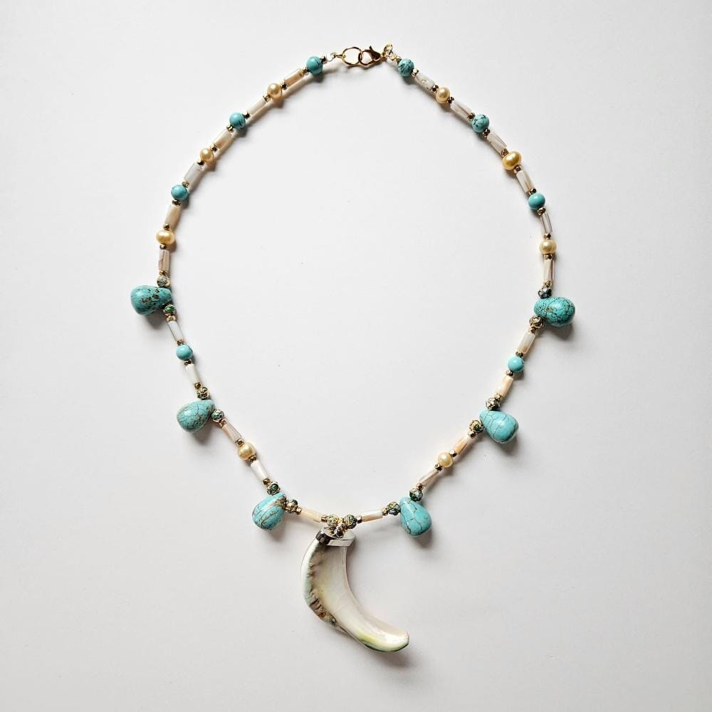 Overview of amuletic necklace with rare giant green banded turbo marmoratus pendant, with dyed turquoise howlite teardrop beads with cloisonne, gold colored metal faceted spacers. mother-of-pearl tube beads and golden freshwater pearls from the Philippines.